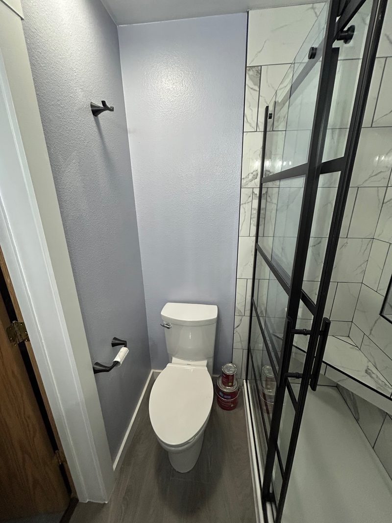 Remodeled guest bathroom with black matte fixtures and marble-look shower tile