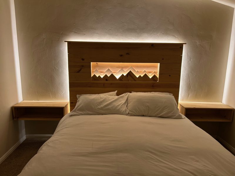 Master suite with custom mountain silhouette LED headboard in Utah custom home