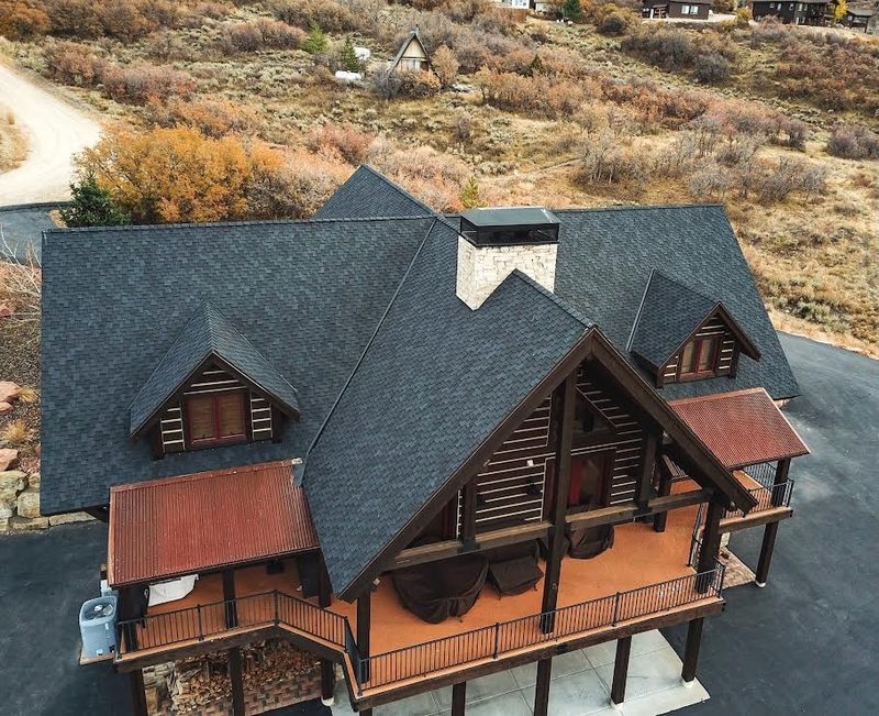 Rear aerial of a custom-built Wasatch mountain home with timber deck and shingle roof in Alpine, Utah
