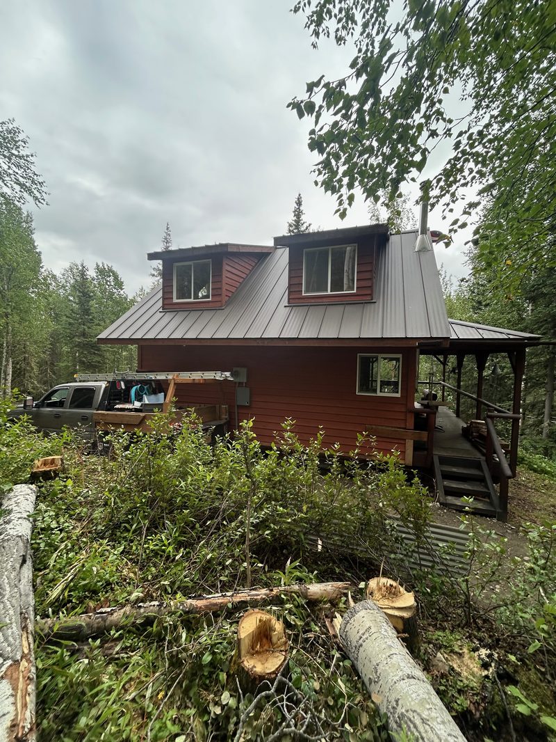 Red-stained cabin exterior with standing seam metal roof built by PrimeWest Construction
