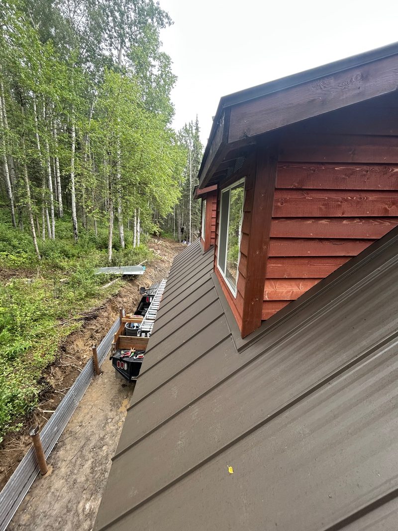 Close-up detail of red cabin siding installation with metal roof edge